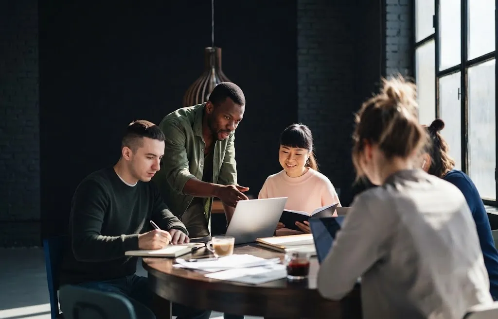 A marketing team working together around a table with laptops and notebooks
